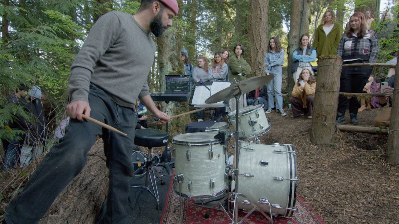 A side profile shot of John standing next to the kit as the audience watches from the trail.