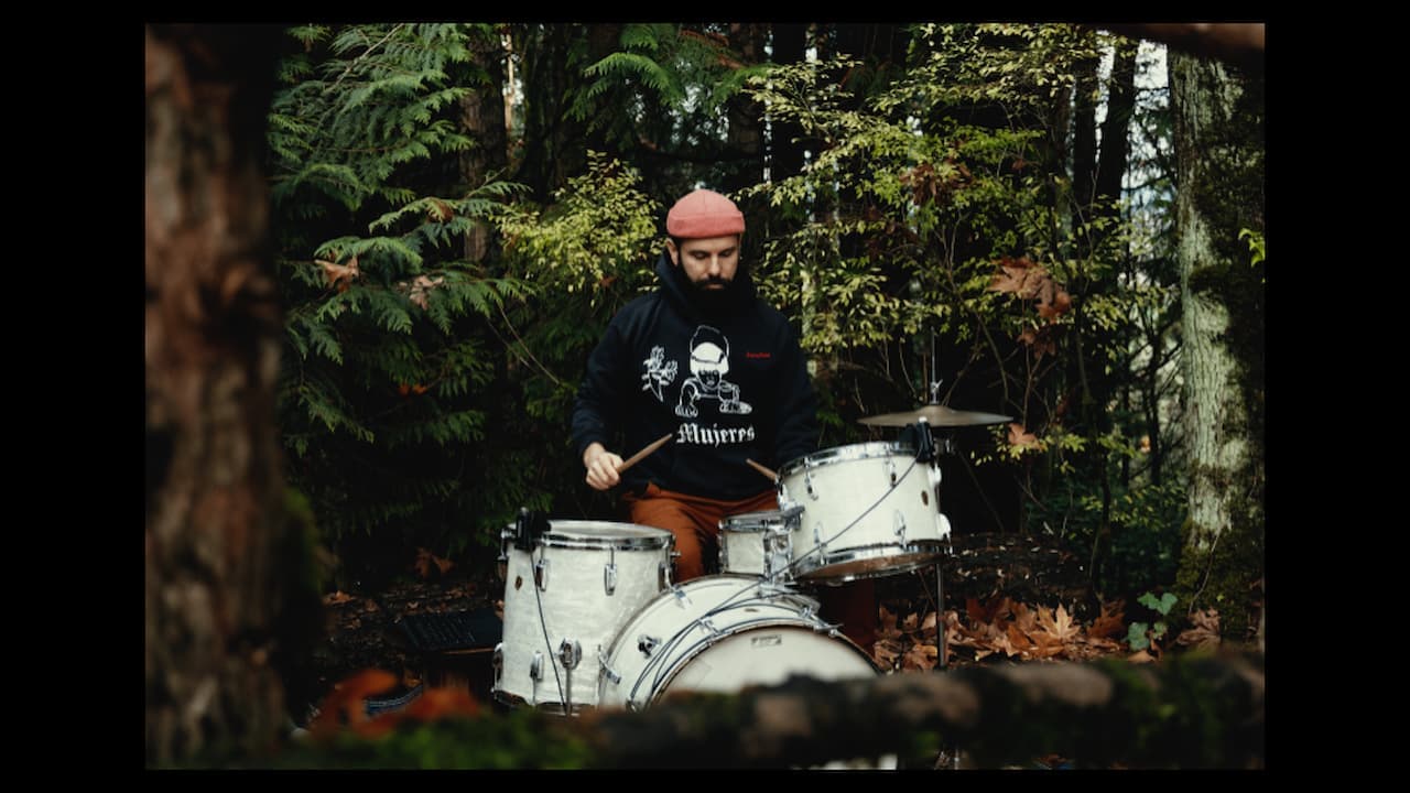 A shot from in front of John with a green forest behind him.