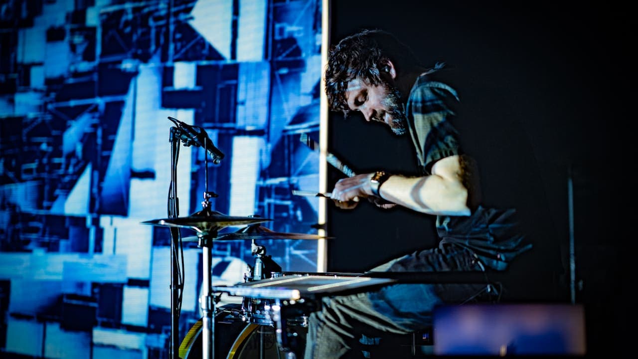 A photo of Brett Bolton performing with his visuals projected next to his drum set.