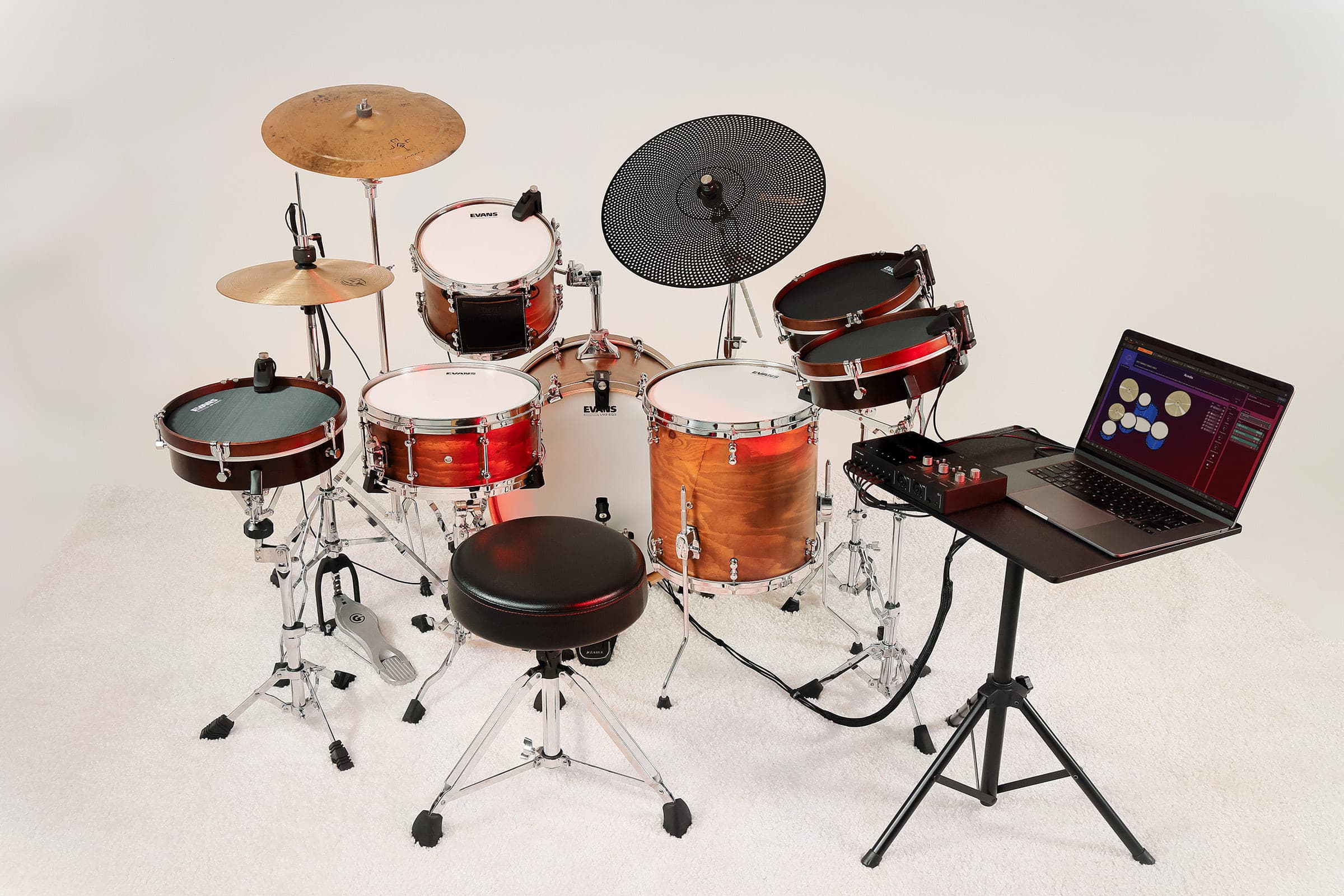 A full hybrid drum kit outfitted with drum, cymbal, and hi-hat sensors, connected to the Portal interface and a laptop running Sensory Percussion