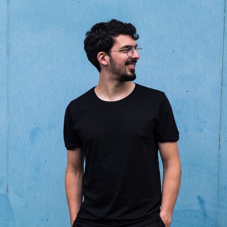 Antoine Pierre smiling, standing in front of a blue background