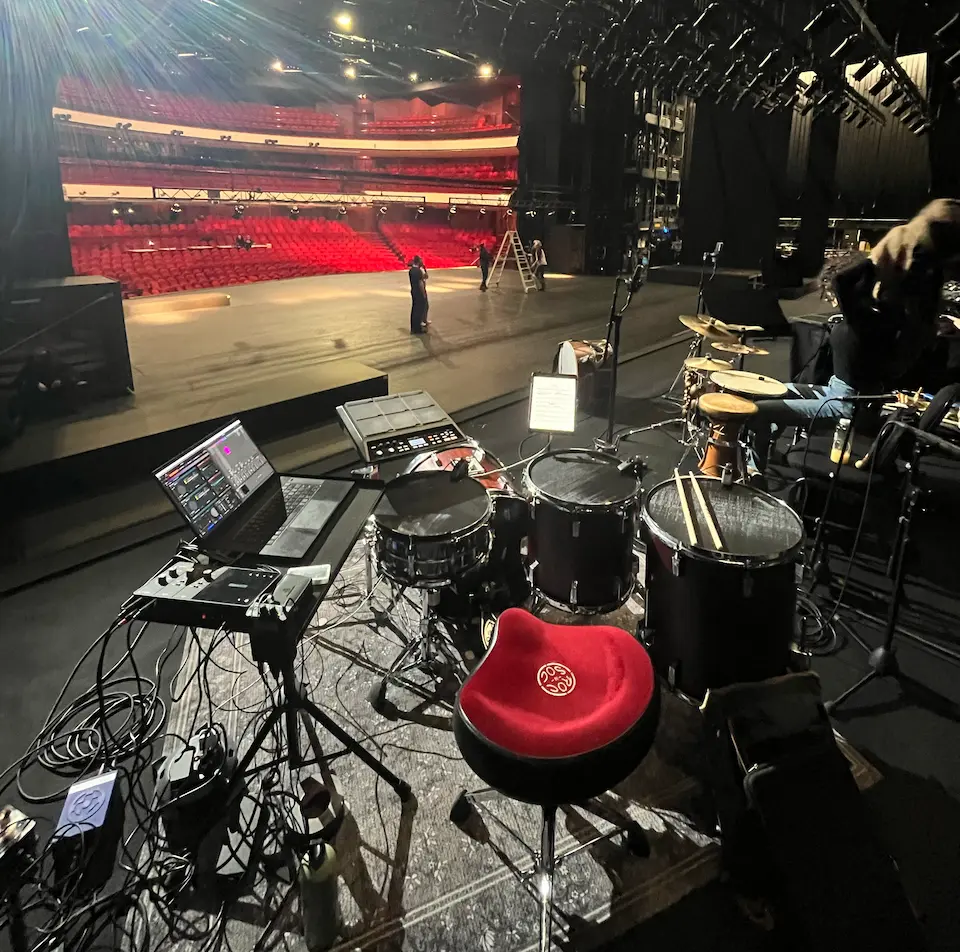 A shot from behind the drum kit showing a large theatre stage