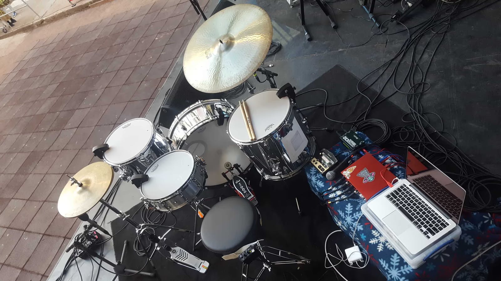 A picture of a Sensory Percussion equipped drumset (silver shells) with a hi-hat and ride cymbal and an audio interface and a few other electronics