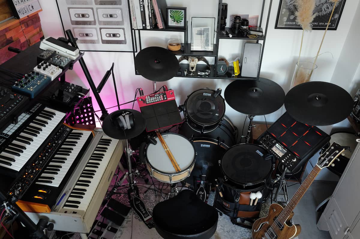 A photo from behind the kit showing Sensory Percussion on mesh drums with rubber cymbals, three keyboard synths to the left of it, and a guitar to the right