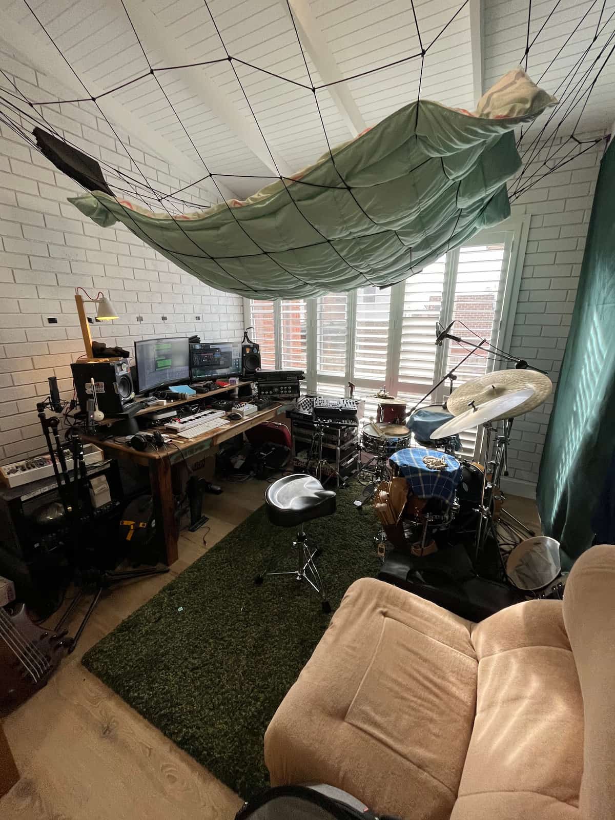A wide shot of Pete's entire studio featuring a drum, lost of pedals, a desk, and DIY sound treatment above the drums
