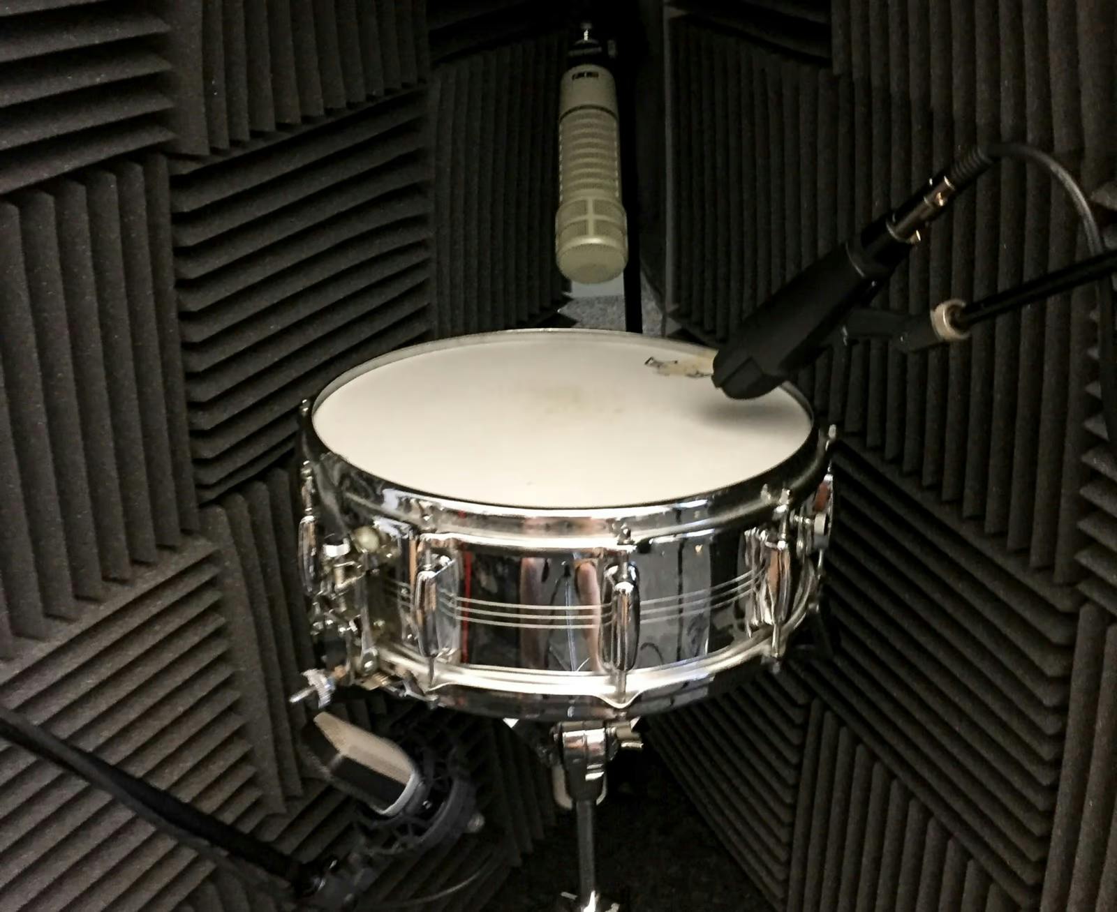 An image of a metal snare with three microphones, two pointed at the batter head, one pointed at the resonant head
