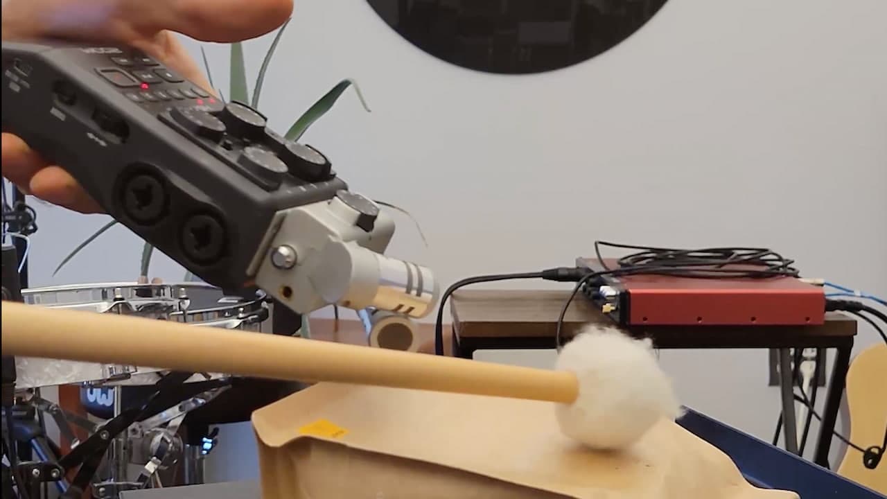 A photo of a mallet hitting a bag of coffee with a Zoom recorder above it to record the audio
