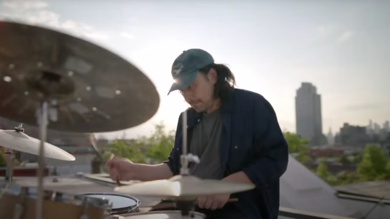 A still of Tlacael Esparza playing drums on a rooftop